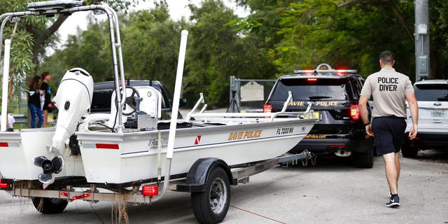 Police divers haul a boat to the entrance of Silver Lakes Rotary Nature Park after a woman was dragged into the lake by an alligator.