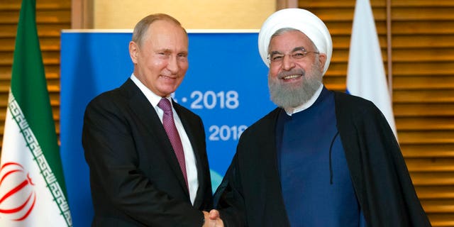 Russian President Vladimir Putin, left, shakes hands with Iranian President Hassan Rouhani during their meeting in Qingdao, China, Saturday, June 9, 2018.