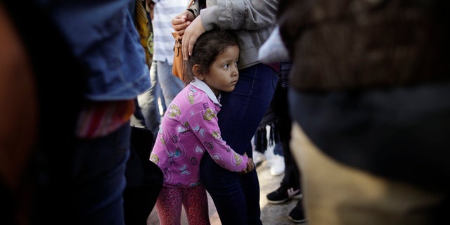 Nicole Hernandez, of the Mexican state of Guerrero, holds on to her mother as they wait with other families to request political asylum in the United States, across the border in Tijuana, Mexico. The family has been waiting for about a week in this border city hoping for a chance to escape widespread violence in their home state.