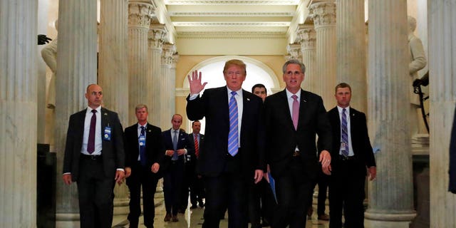President Donald Trump, center, accompanied by House Majority Leader Kevin McCarthy of Calif., waves as he departs Capitol Hill in Washington, Tuesday, June 19, 2018, after a meeting to rally Republicans around a GOP immigration bill.  (AP Photo/Alex Brandon)