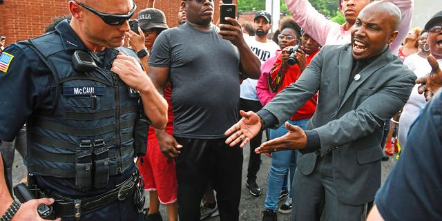 Leonard Hammonds II, of Penn Hills, right, points out that a Turtle Creek Police officer has his hand on his weapon during a rally in East Pittsburgh, Pa., on Wednesday, June 20, 2018, at a protest regarding the shooting death of Antwon Rose by an East Pittsburgh Police officer during a traffic stop the night before.
