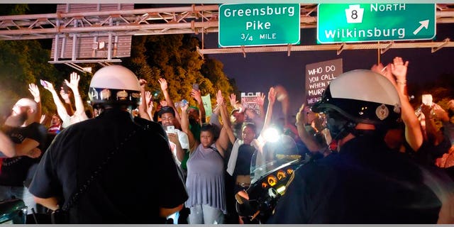Protesters chant "Hands up! Don't shoot!" at motorcycle officers near the head of a line of vehicles stuck on Interstate 376 in Pittsburgh on Thursday, June 21, 2018. The highway was shut down by the people protesting the East Pittsburgh police after the June 19 shooting death of Antwon Rose, a 17-year-old boy fatally shot by a police officer in Pennsylvania seconds after he fled a traffic stop