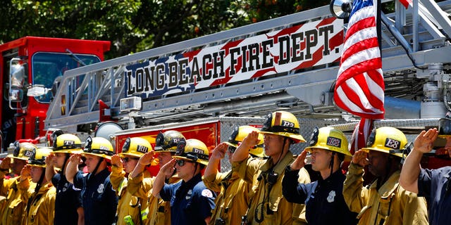 Firefighters salute during a procession for Fire Capt. Dave Rosa who was killed after he was shot responding to an emergency at a senior home in Long Beach, California, on Monday, June 25, 2018.