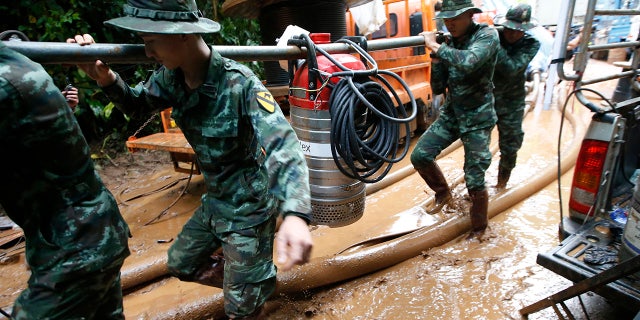 Thai soldiers carry a water pump to drain the cave where 12 boys and their soccer coach had been missing in Mae Sai, Chiang Rai province in northern Thailand.