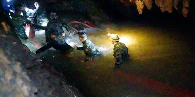 In this handout photo released by Tham Luang Rescue Operation Center, Thai rescue teams walk inside cave complex where 12 boys and their soccer coach went missing, in Mae Sai, Chiang Rai province, in northern Thailand, Monday, July 2