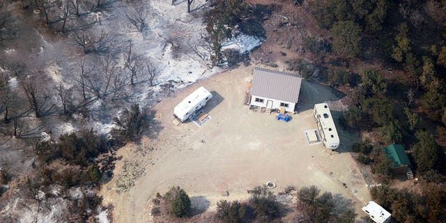 A burnt out structure is visible through the smoke as a wildfire continues to burn east of Strawberry Reservoir, in Wasatch County, Utah, Tuesday, July 3, 2018.