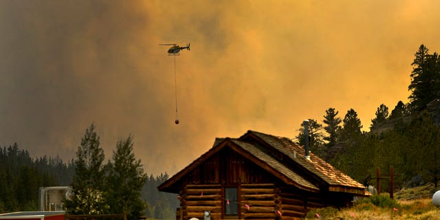 In this Monday, July 2, 2018 photo, a helicopter returns for water after making a water drop on a wildfire near Fairplay, Colorado.