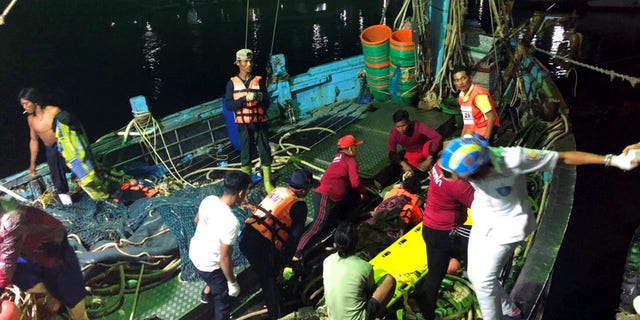 Rescued tourists from a boat that sank are helped onto a pier from a fishing boat Thursday, July 5, 2018, on the island of Phuket, southern Thailand.