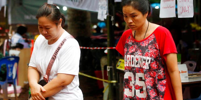 Concerned family members walk and wait near the cave where the boys are trapped