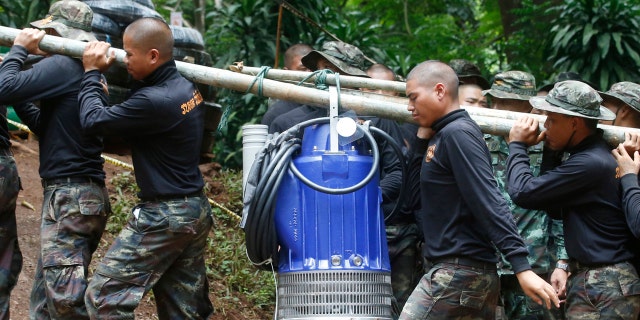 Soldiers carry a pump to help drain the rising flood water in a cave where 12 boys and their soccer coach have been trapped since June 23, in Mae Sai, Chiang Rai province, in northern Thailand Friday, July 6, 2018.