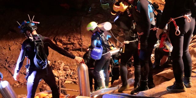 In this undated photo released by Royal Thai Navy on Saturday, July 7, 2018, Thai rescue team members walk inside a cave where 12 boys and their soccer coach have been trapped since June 23.