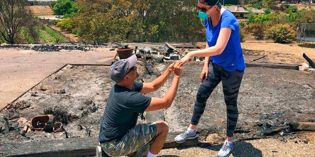 Ishu Rao gets down on one knee to return his wife's wedding ring to her next to the charred remains of their Goleta, Calif. home.