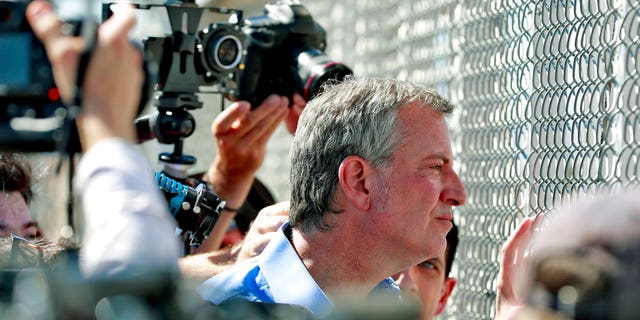 New York City Mayor Bill de Blasio looks through a closed gate at the Port of Entry facility, in Fabens, Texas, where tent shelters are being used to house separated family members..