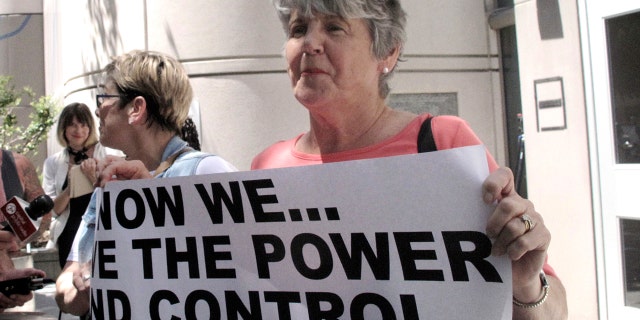 Jane Carson-Sandler, of South Carolina, who was raped in 1976, holds a sign with a message to her alleged attacker, the so-called "Golden State Killer" suspect, in Sacramento, Calif., July 12, 2018.