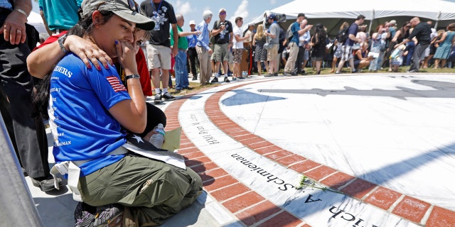 Morgan Zoufal, is comforted as she reacts to seeing the name of her late fiancee, Marine Sgt. Dietrich A. Schmieman, on a marble monument, honoring the 15 Marines and a U.S. Navy corpsman who died in a 2017 plane crash near Itta Bena, Miss., Saturday, July 14, 2018.