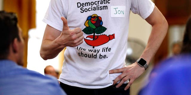 Jon Torsch, center, wears a t-shirt promoting democratic socialism during a gathering of the Southern Maine Democratic Socialists of America at City Hall in Portland, Maine, Monday, July 16, 2018. On the ground in dozens of states, there is new evidence that democratic socialism is taking hold as a significant force in Democratic politics. (AP Photo/Charles Krupa)