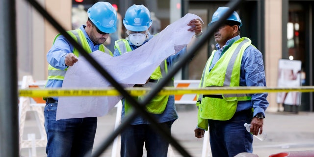 Con Edison workers look at a map of pipes on New York's Fifth Avenue, Thursday, July 19, 2018.
