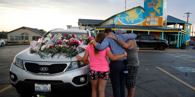 People pray by a car thought to belong to a victim of Thursday's boating accident before a candlelight vigil in the parking lot of Ride the Ducks Friday, July 20, 2018, in Branson, Mo.