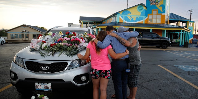 People pray by a car thought to belong to a victim of Thursday's boating accident before a candlelight vigil in the parking lot of Ride the Ducks Friday, July 20, 2018, in Branson, Mo.
