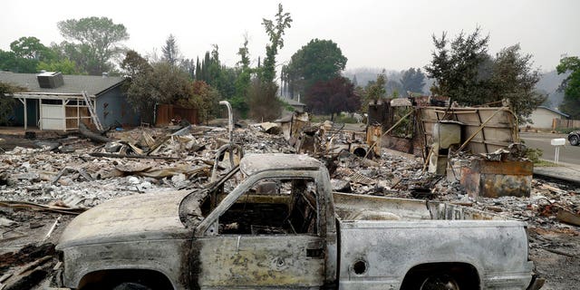 A burned out vehicle sits in front of a wildfire-ravaged home Saturday, July 28, 2018, in Redding, California.