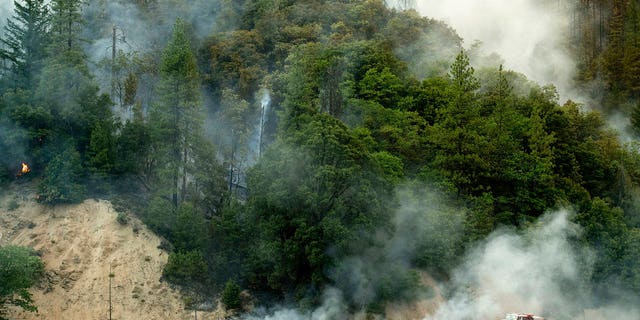 A fire truck passes a smoldering hillside as the Carr Fire burns along Highway 299 in unincorporated Shasta County, California, on Saturday, July 28, 2018.