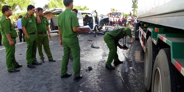 Police examine the scene after a wedding van collided with a container truck in Quang Nam province, Vietnam.