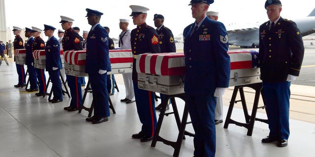 Military members stand at attention after placing transfer cases in a hanger at a ceremony marking the arrival of the remains believed to be of American service members who fell in the Korean War at Joint Base Pearl Harbor-Hickam in Hawaii, Wednesday, Aug. 1, 2018.