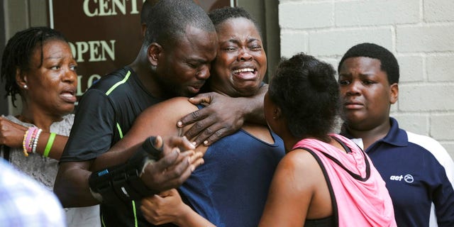 The mother, center, of two young children is comforted after she found them stabbed to death in their father's apartment in Houston.
