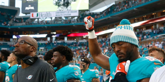 Miami Dolphins defensive end Robert Quinn (94) raises his right fist during the singing of the national anthem, before the team's NFL preseason football game.