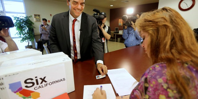 In this July 15, 2014 file photo, Silicon Valley venture capitalist Tim Draper presents his drivers license as he turns in boxes of petitions for a ballot initiative that would ask voters to split California into six separate states in Sacramento, Calif.