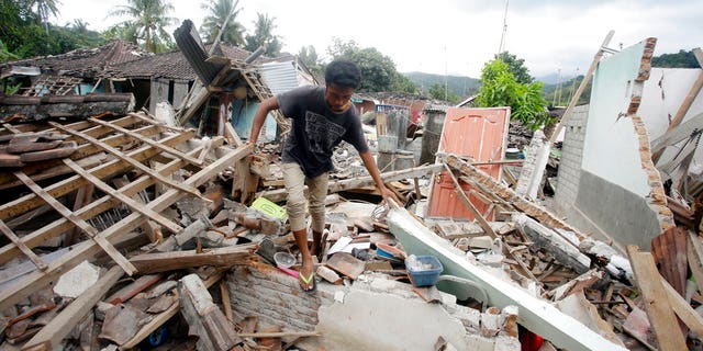 A man walks through debris from Sunday's earthquake in West Lombok, Indonesia, Saturday