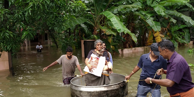 An elderly woman is rescued in a cooking utensil after her home was flooded in Thrissur, Kerala state, India.