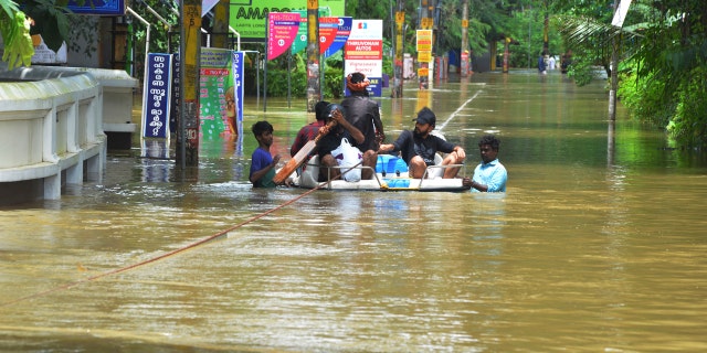 People move past a flooded area in Thrissur, in the southern Indian state of Kerala, Friday, Aug. 17, 2018.