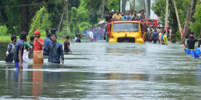 A truck carries people past a flooded road in Thrissur, in the southern Indian state of Kerala, Saturday, Aug. 18, 2018.