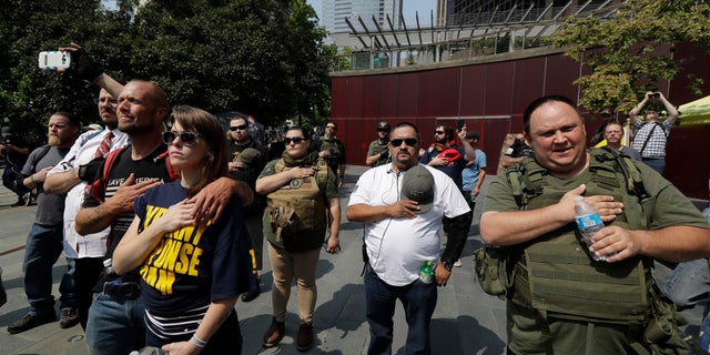 Supporters of Second Amendment gun rights stand during a playing of a recording of the national anthem outside City Hall in Seattle, Aug. 18, 2018.