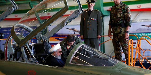 Iranian President Hassan Rouhani is briefed by an air force pilot as he sits in the cockpit of a fighter jet on Tuesday