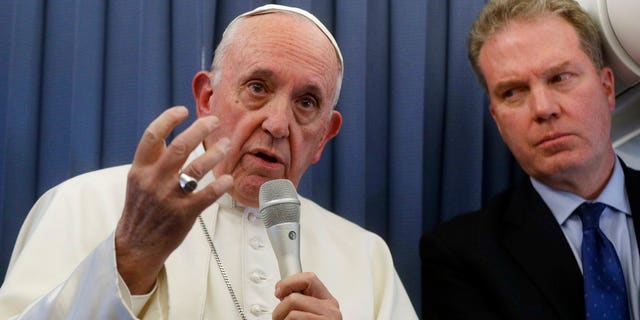 Pope Francis, flanked by Vatican spokesperson Greg Burke, listens to a journalist's question during a press conference aboard of the flight to Rome at the end of his two-day visit to Ireland, Sunday