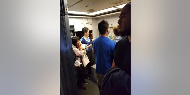 Passengers and crew members gather in a back galley on a Hawaiian Airlines flight from Oakland, Calif., to Kahului, Hawaii, after a can of pepper spray went off inside the plane, Aug. 31, 2018.