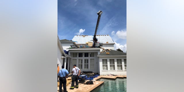 This photo released by the Orlando Fire Department shows firefighters surveying the scene where a crane tipped over, damaging a house in Orlando, Fla., on Tuesday.