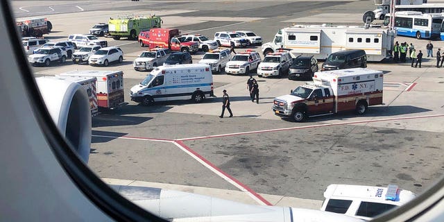 Emergency response crews gather outside a plane at New York's Kennedy Airport amid reports of ill passengers aboard a flight from Dubai on Wednesday.