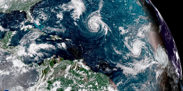 This enhanced satellite image made available by NOAA shows Tropical Storm Florence, center, in the Atlantic Ocean on Saturday, Sept. 8, 2018 at 2:45 p.m. EDT.