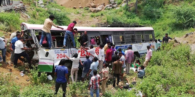 Rescuers pull out passengers from a bus that fell into a gorge in Jagtiyal district of Telangana, India, Tuesday, Sept. 11, 2018. A bus carrying pilgrims from a Hindu temple in the hills of south India plunged off a road Tuesday, killing more than 50 people including four children, officials said. (AP Photo)