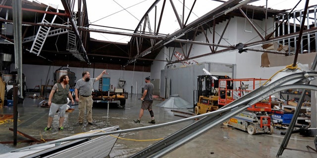 Ethan Hall, right, Michael Jenkins, center, and Nash Fralick, left, examine damage to Tidewater Brewing Co. in Wilmington, N.C., after Hurricane Florence made landfall.