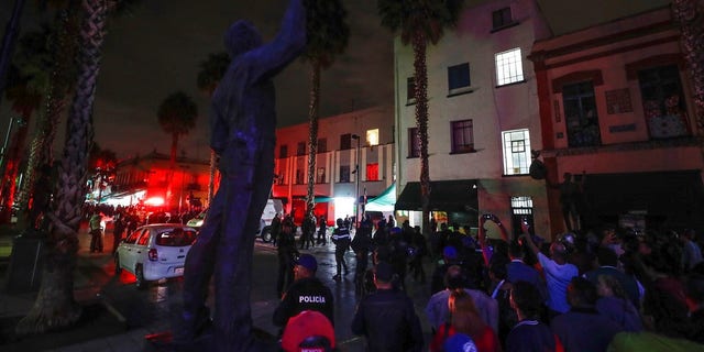 Curious onlookers gather on the perimeters of a crime scene after a shooting in Garibaldi Plaza in Mexico City.