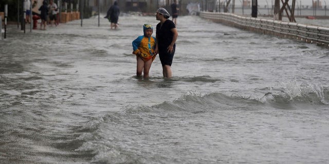 People walk through floodwaters caused by Typhoon Mangkhut on the waterfront in Hong Kong.