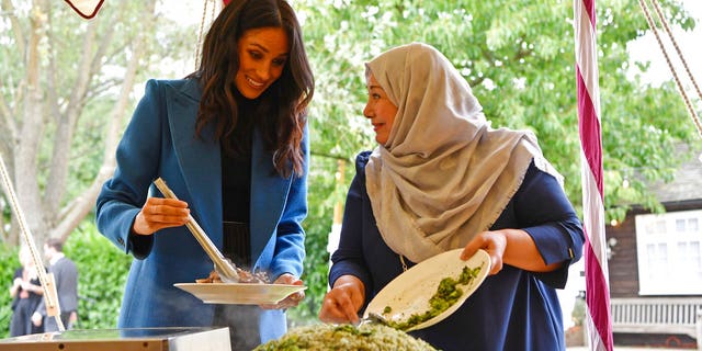 Meghan, the Duchess of Sussex, left, reacts with one of the women behind the cookbook "Together" during a reception at Kensington Palace.