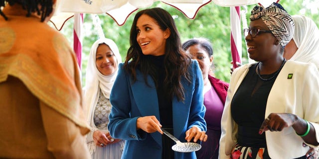 Meghan, the Duchess of Sussex, centre, reacts with one of the women behind the cookbook "Together" during a reception at Kensington Palace.
