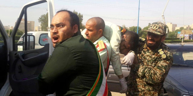 Revolutionary Guard members carry a wounded comrade after a shooting during their parade marking the 38th anniversary of Iraq's 1980 invasion of Iran, in the southwestern city of Ahvaz, Iran, Saturday, Sept. 22, 2018.