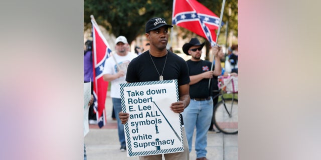 An unidentified participant holds a sign during a December rally led by the Take 'em Down Coalition, as confederate heritage supporters bear confederate flags nearby in front of City Hall in New Orleans.