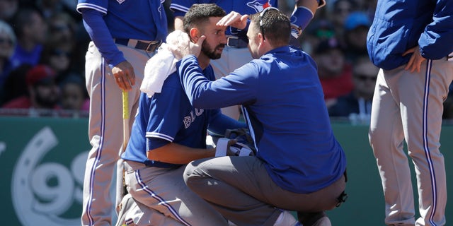 Toronto Blue Jays' Chris Colabello, center left, is tended to after being hit by a pitch in the fourth inning of a baseball game against the Boston Red Sox at Fenway Park, Sunday, April 17, 2016, in Boston. (AP Photo/Steven Senne)